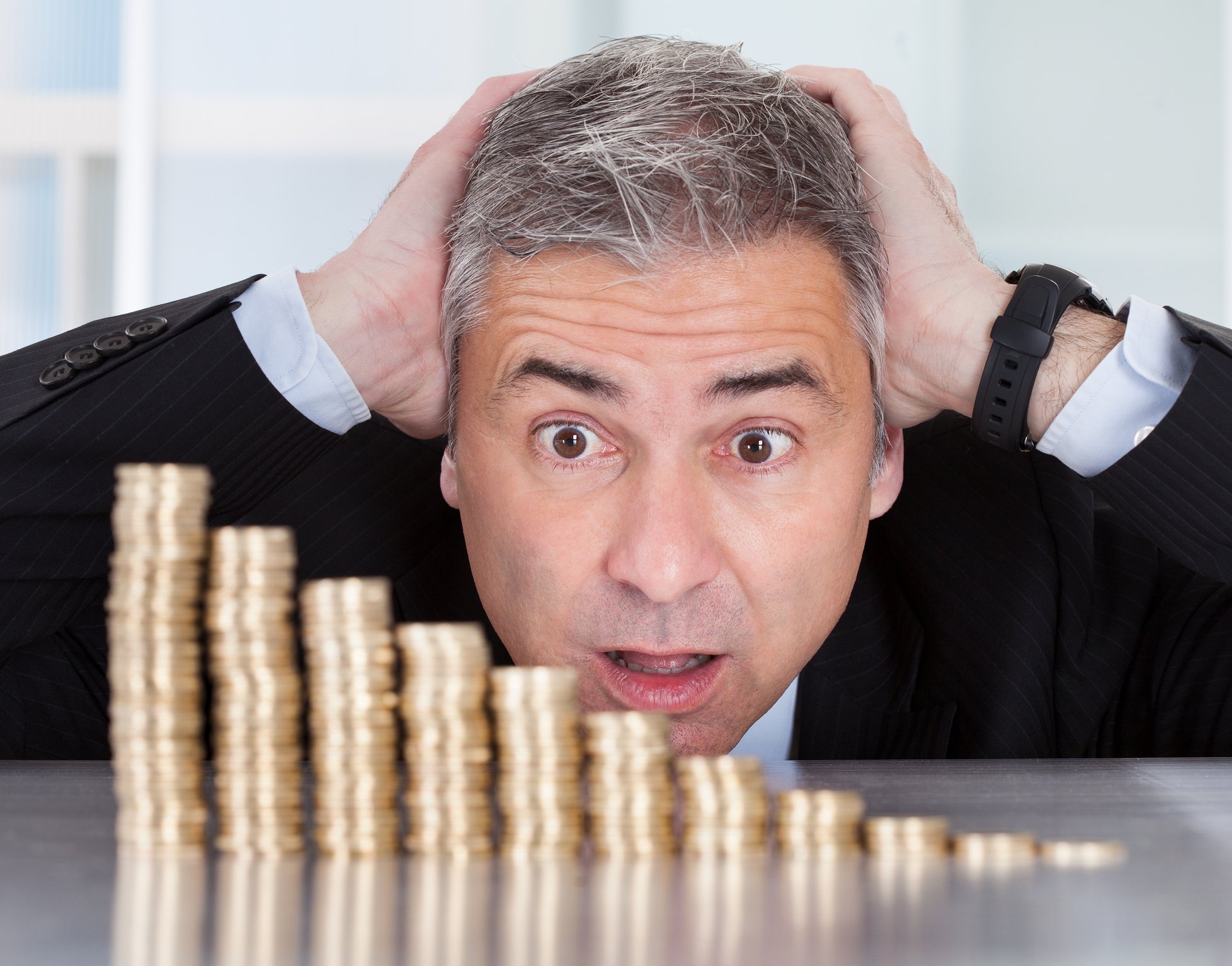 A declining stack of coins in front of a worried investor.