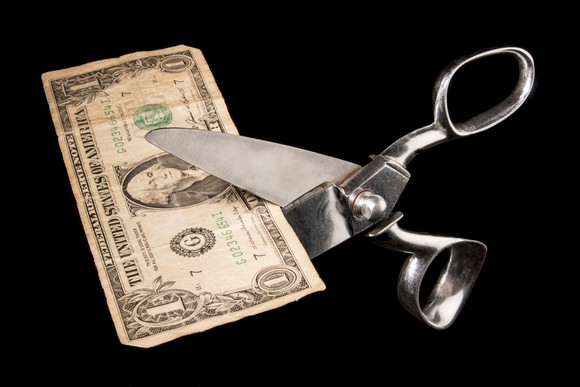 Scissors cutting dollar bill