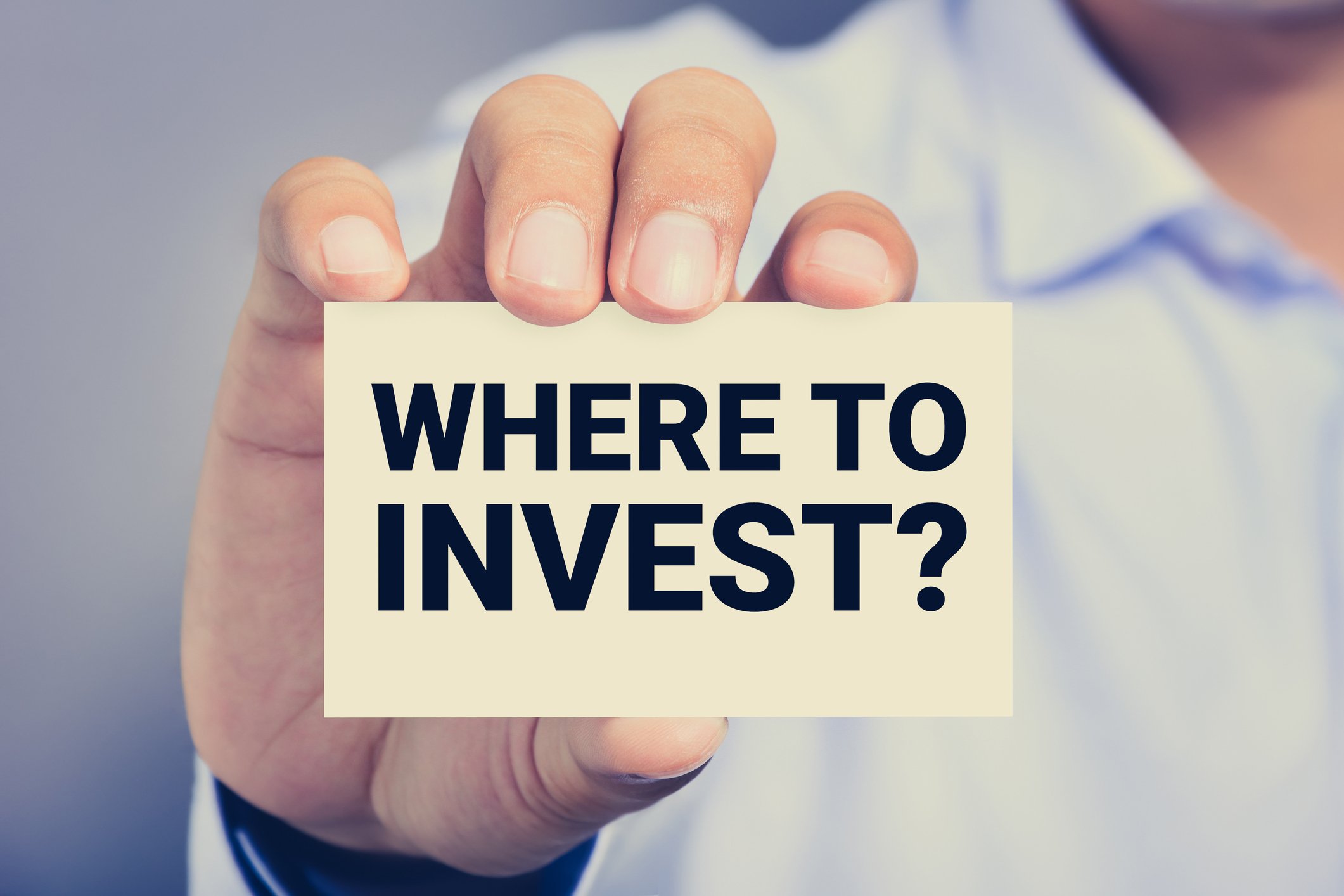 person holding card that says "where to invest"