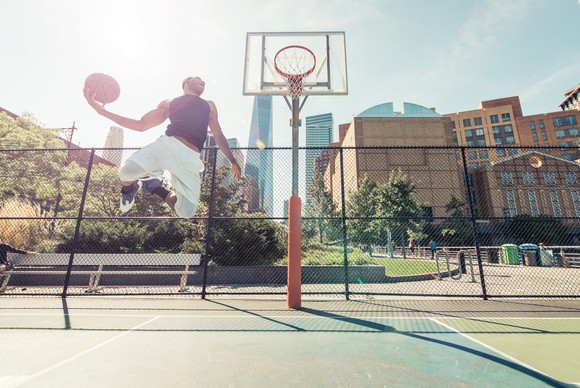 Man performs a slam dunk on a basketball court.