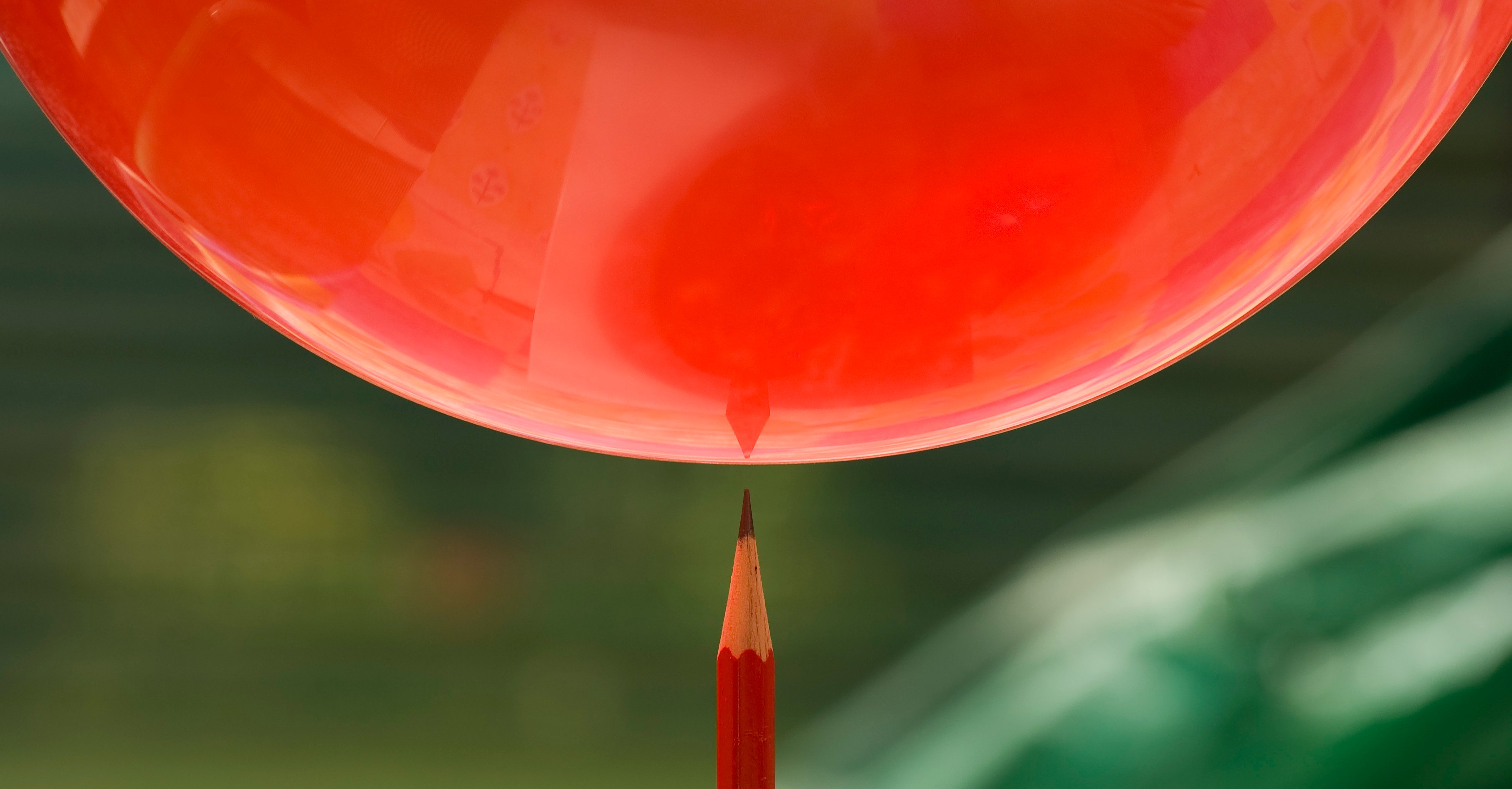 A balloon with a pencil about to pop it.