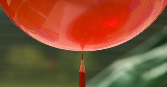 A balloon with a pencil about to pop it.