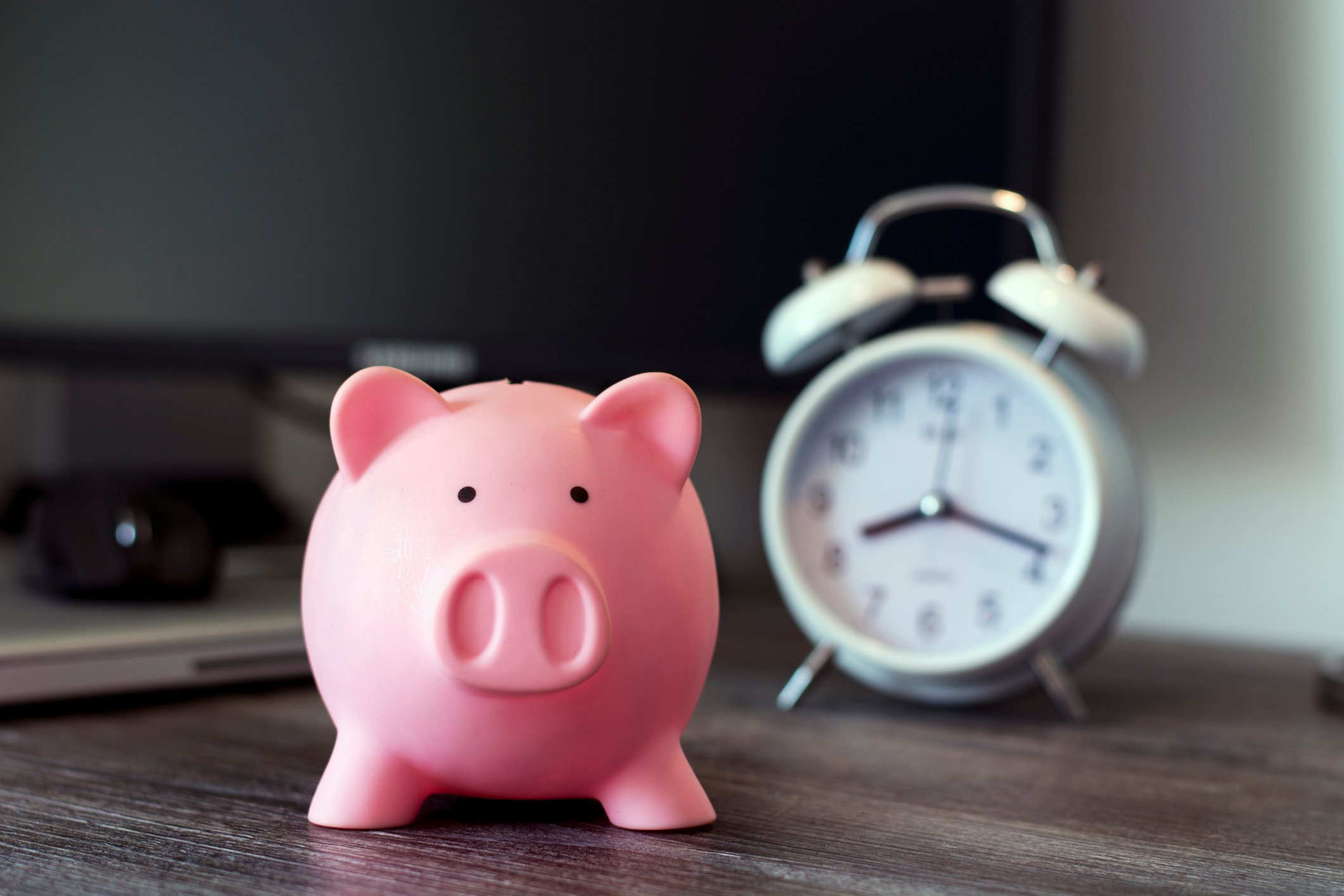 A piggy bank with a clock in the background