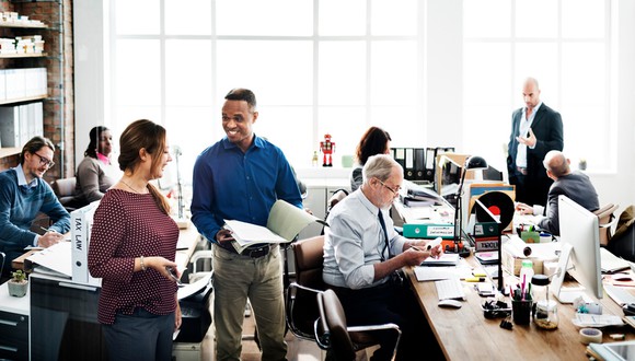 Busy contemporary office with employees in close working quarters.