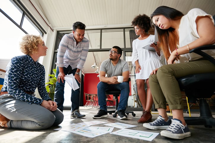 Creative team brainstorming at work with documents on floor