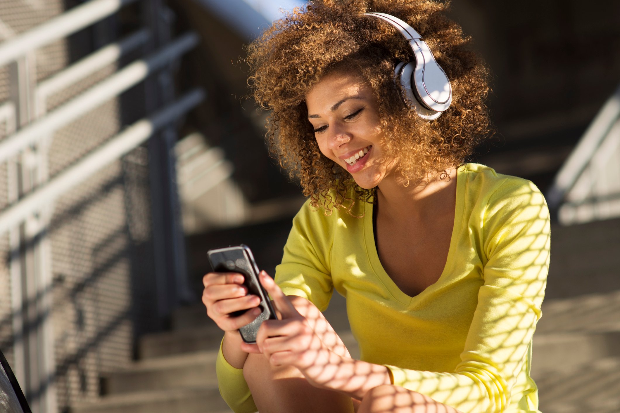 A women using a phone and listening to wireless headphones.