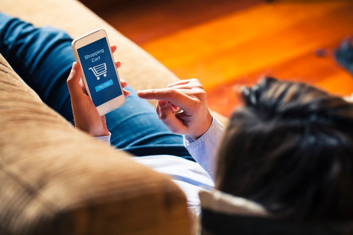 Woman on couch shopping on her cellphone.
