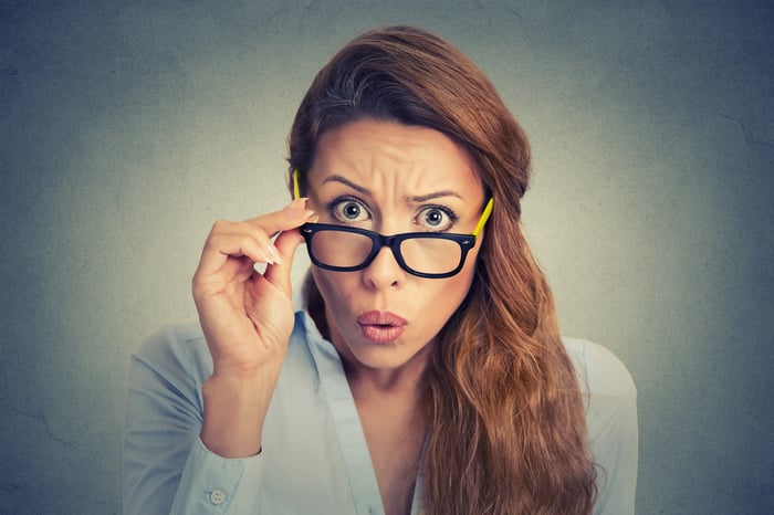 A women looks over the top of her glasses with a surprised expression.