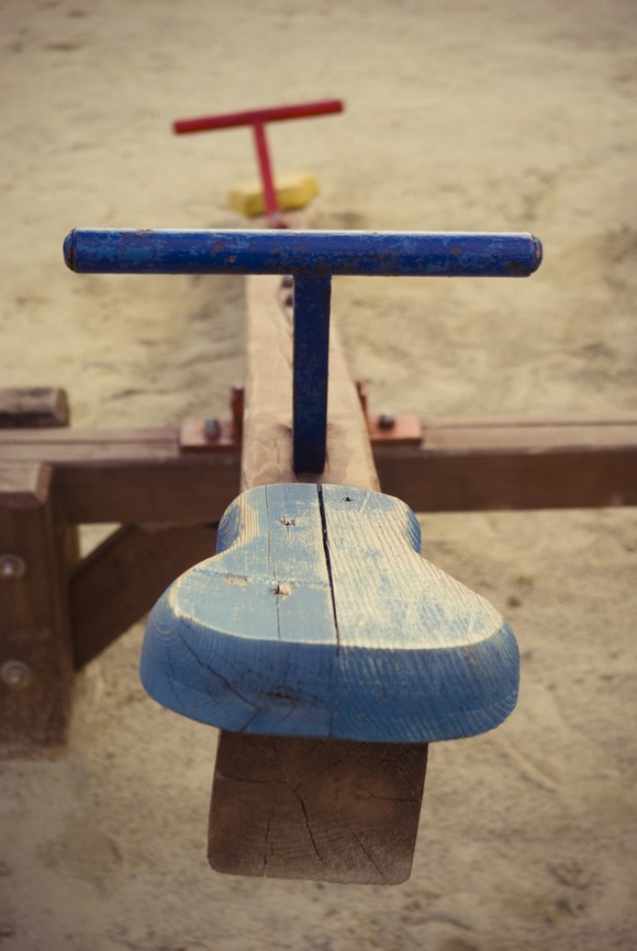 Wooden playground seesaw painted in blue and red.