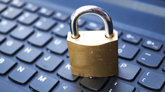 A padlock sits on top of a computer keyboard.