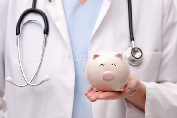 A doctor holding a piggy bank. 