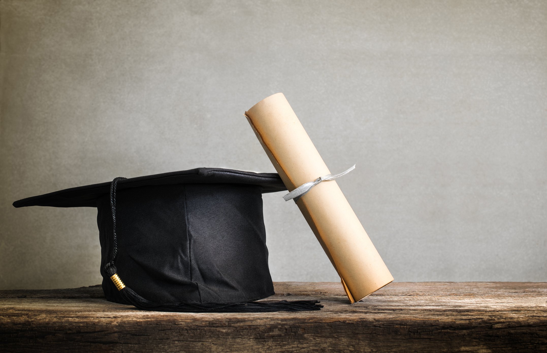 A graduation cap sits with a diploma.