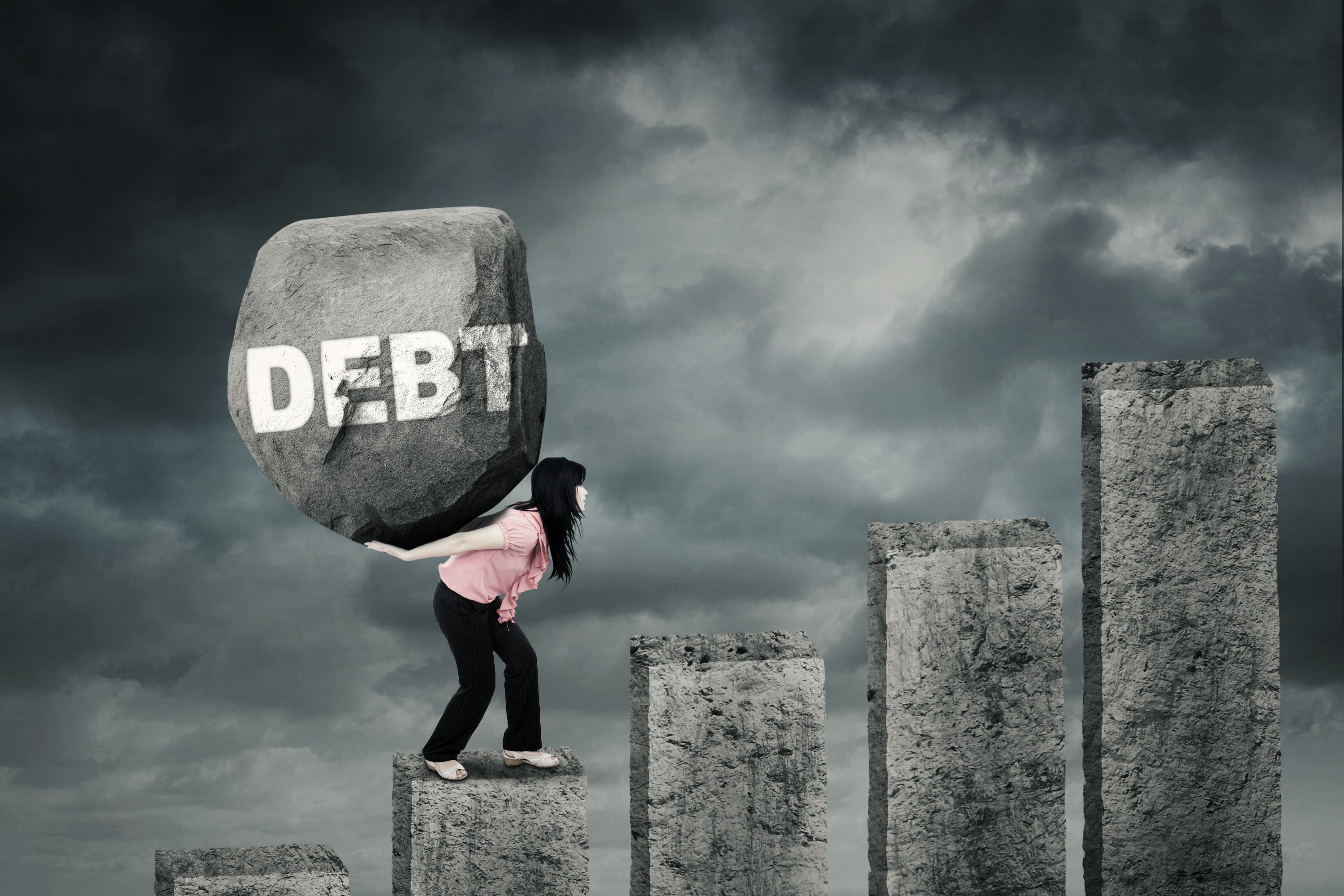 A woman carrying a granite rock labeled debt climbs a mountain of ascending granite pillars.