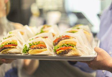 Someone holding a tray of Shake Shack burgers.