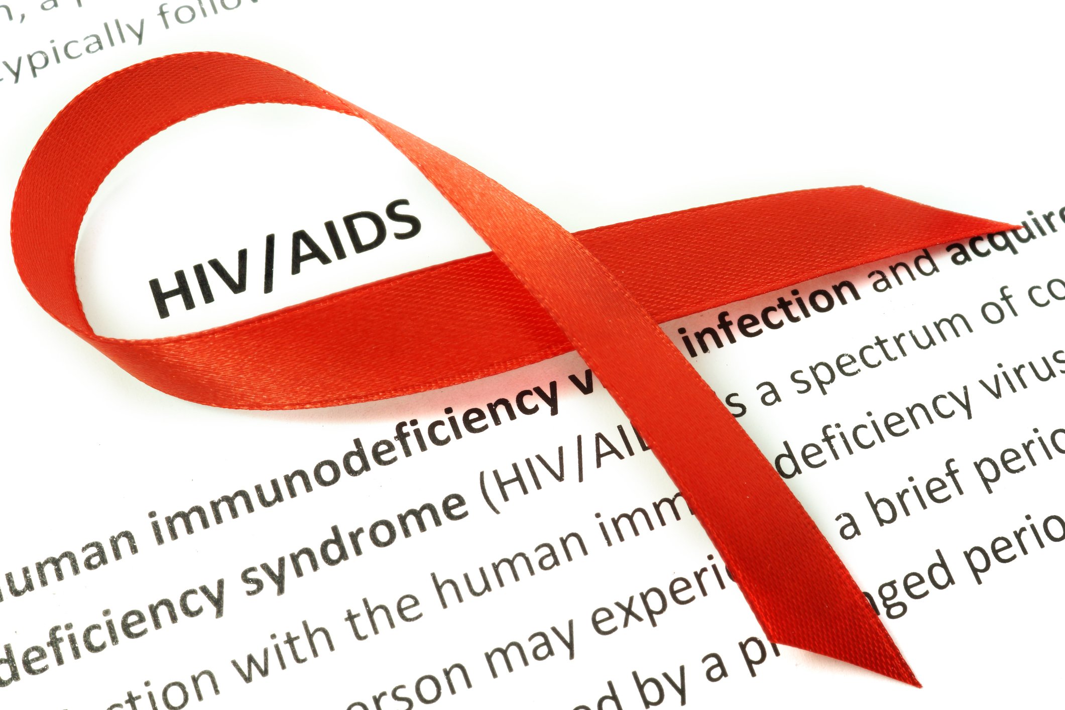 Red ribbon on a paper with definition of HIV/AIDS