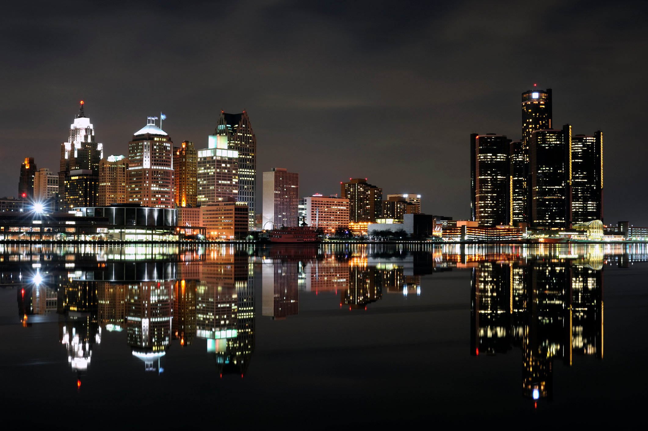 The Detroit skyline at night with it's reflection in the foreground.