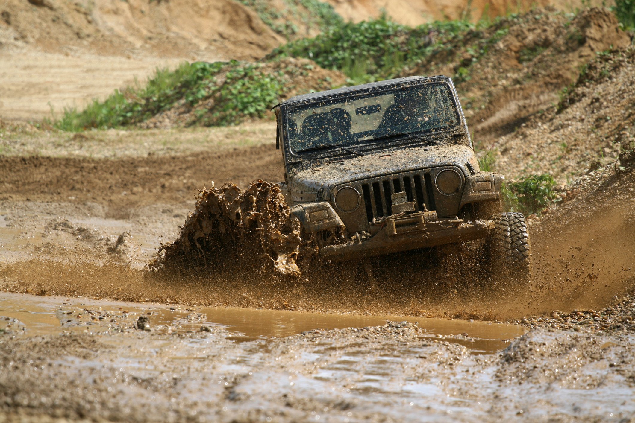 A jeep is driving through mud.