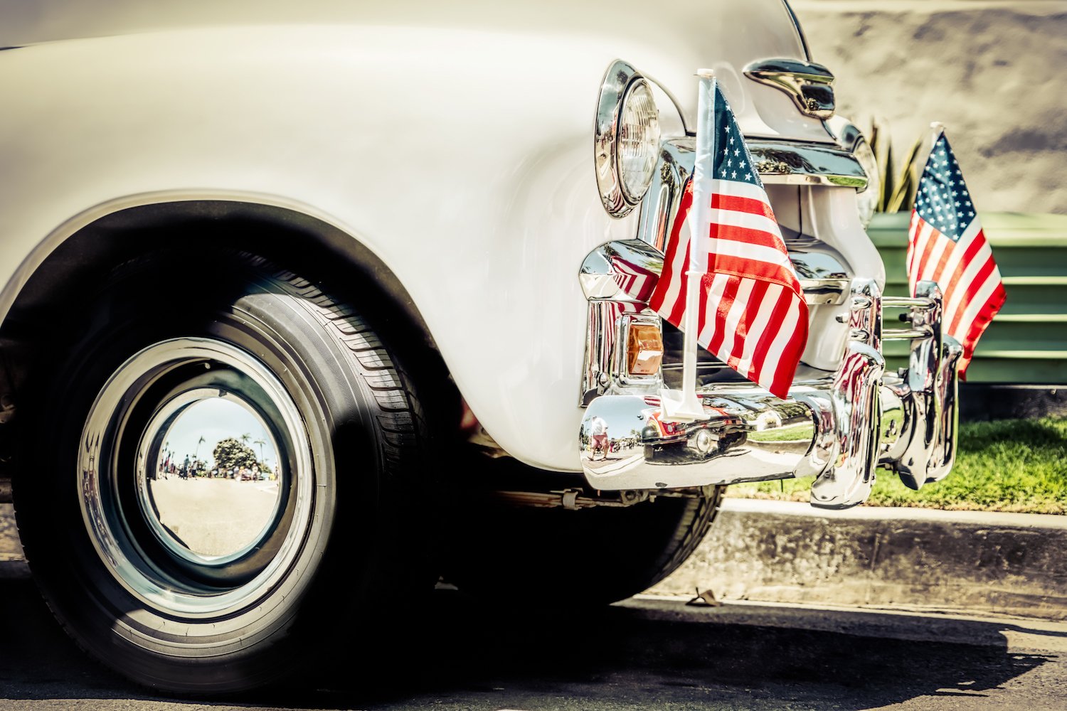 Old car with American flags on the front.