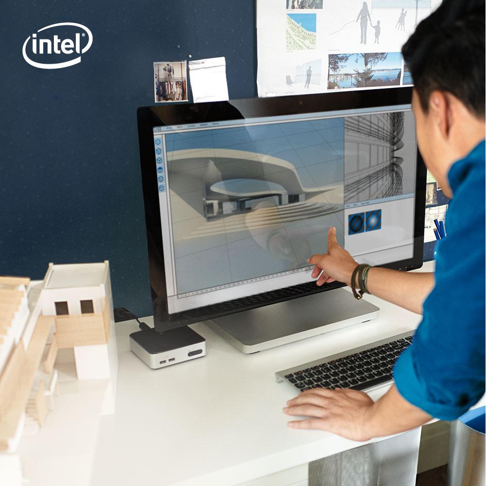A man puts his finger on a computer monitor at an office desk.