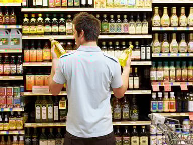 Young man comparing bottles  grocery shopping crop
