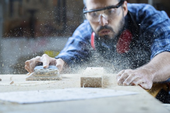 Carpenter blowing sawdust off wood