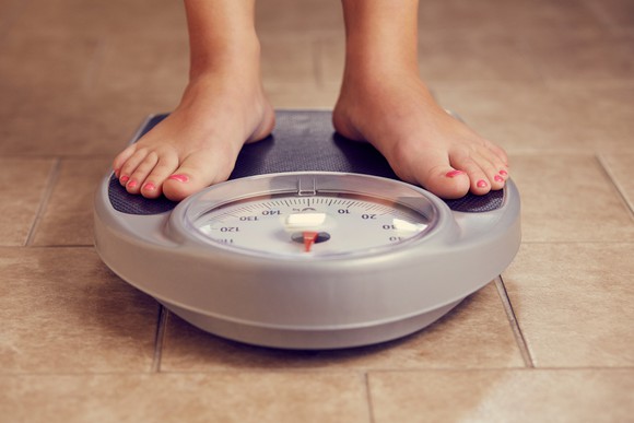 A person stands on a bathroom scale.