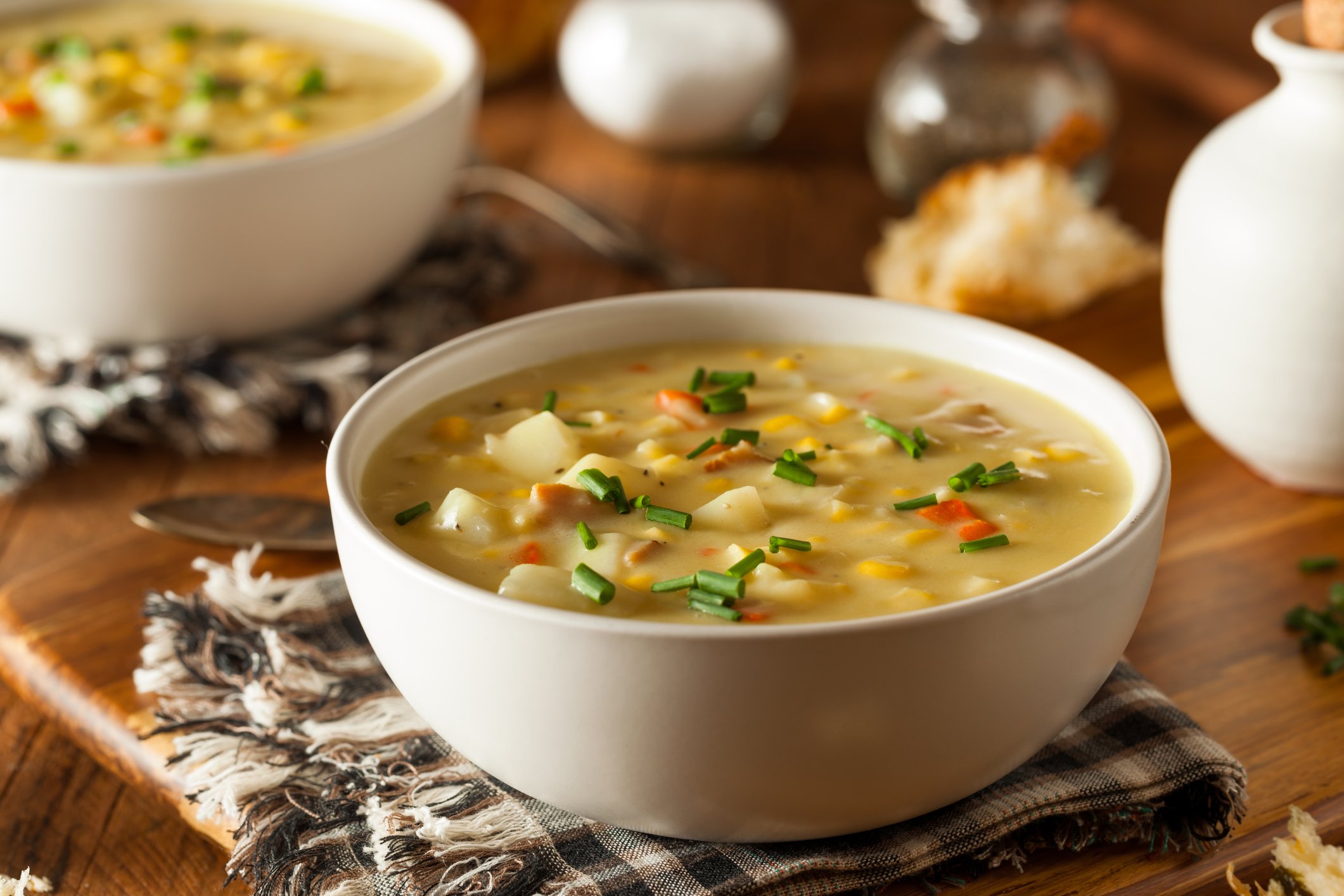 A bowl of corn chowder sits on a dinner table.