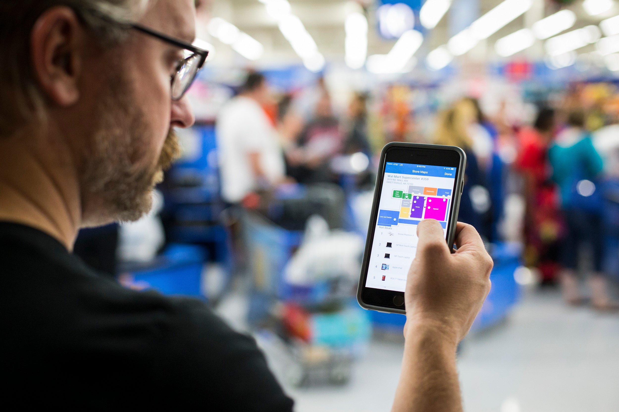 A man holds his phone with the Wal-Mart app open in a Wal-Mart