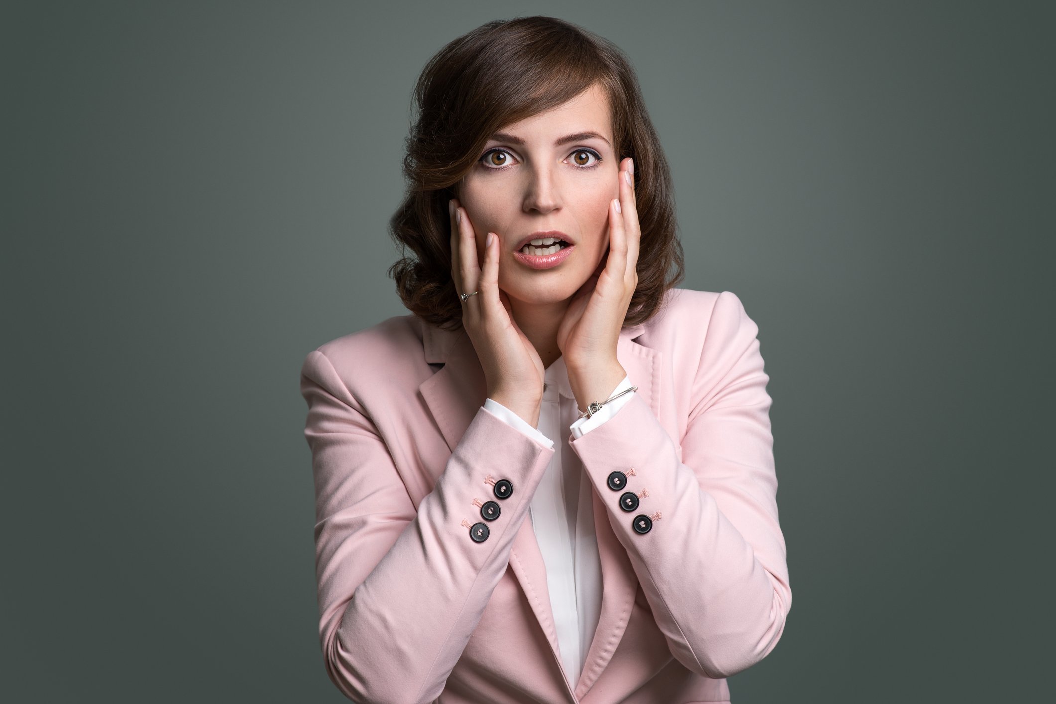 Worried young businesswoman holding hands against cheeks