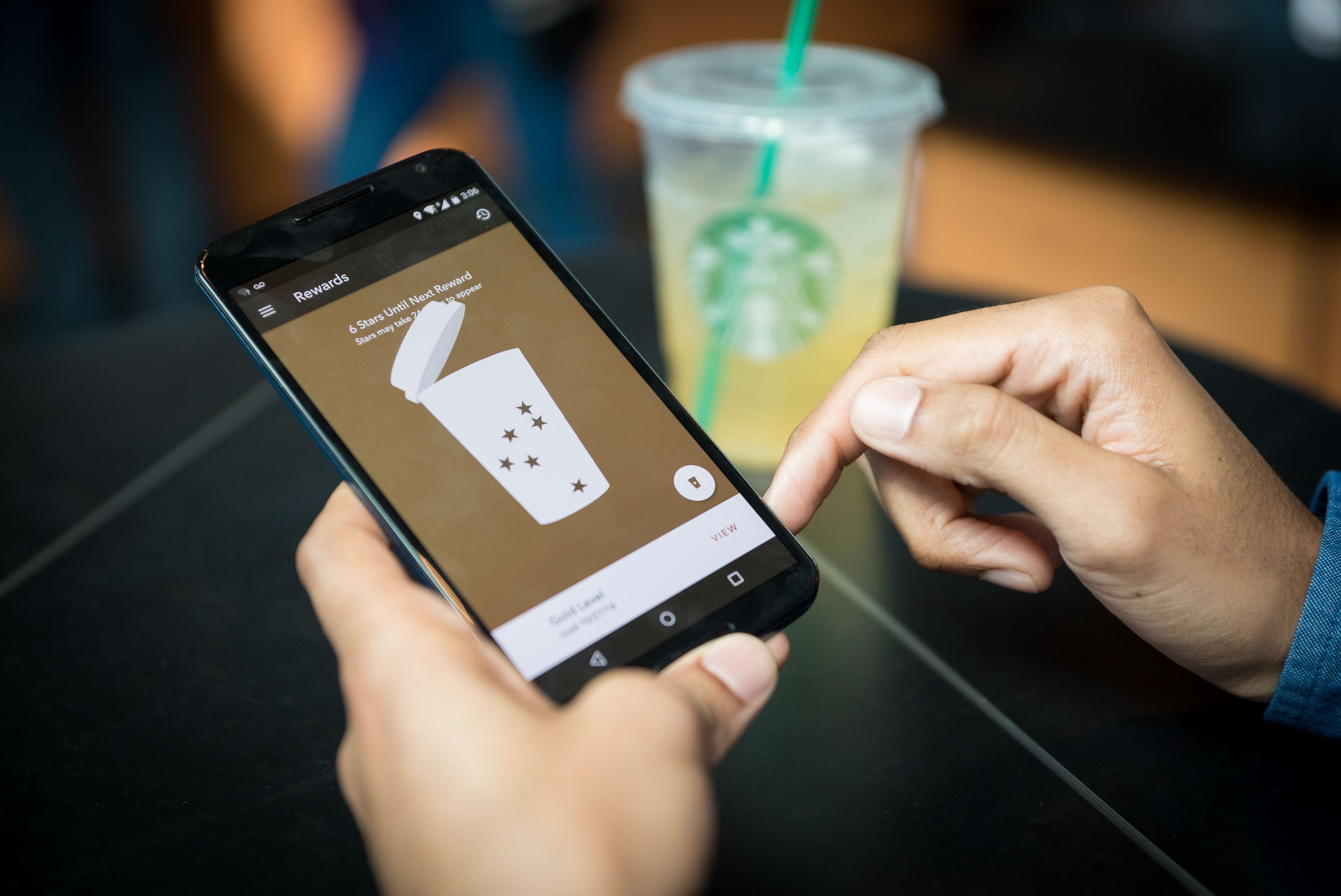 The Starbucks app on an iPhone with Starbucks cup in background