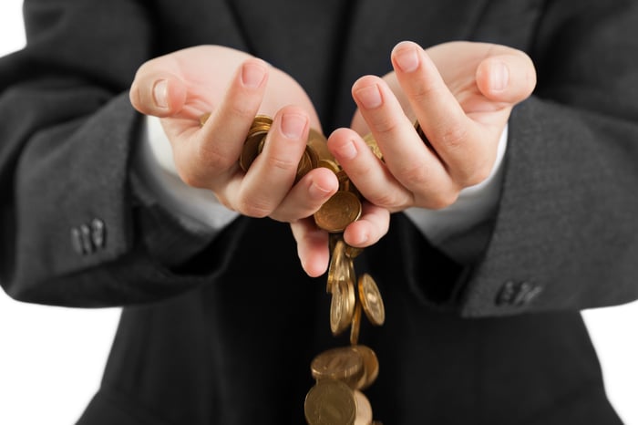 Coins falling through hands.