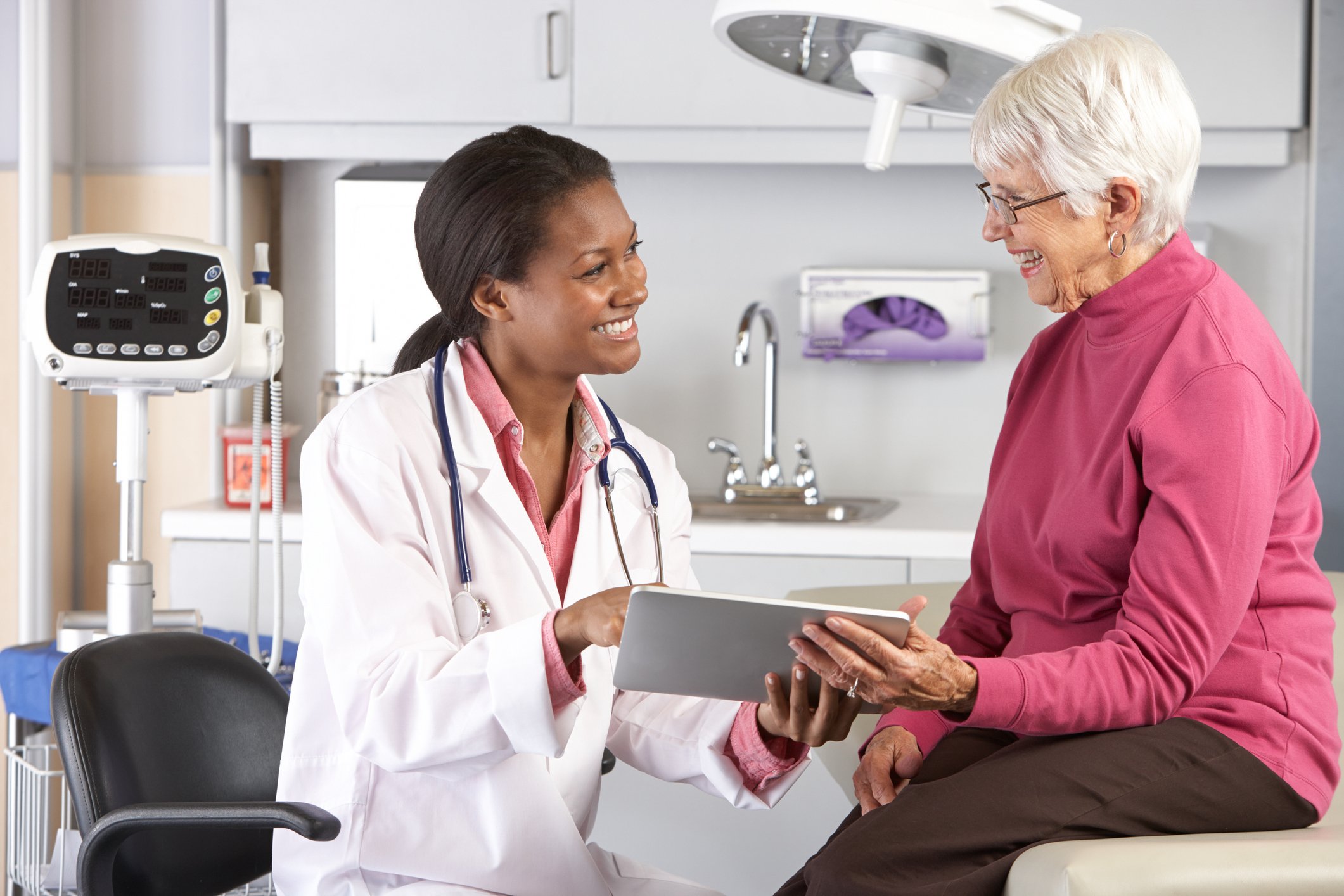 A doctor consults with a senior patient in the exam room.