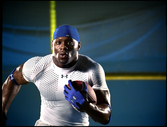 Julius Jones in Under Armour apparel, carrying a football.