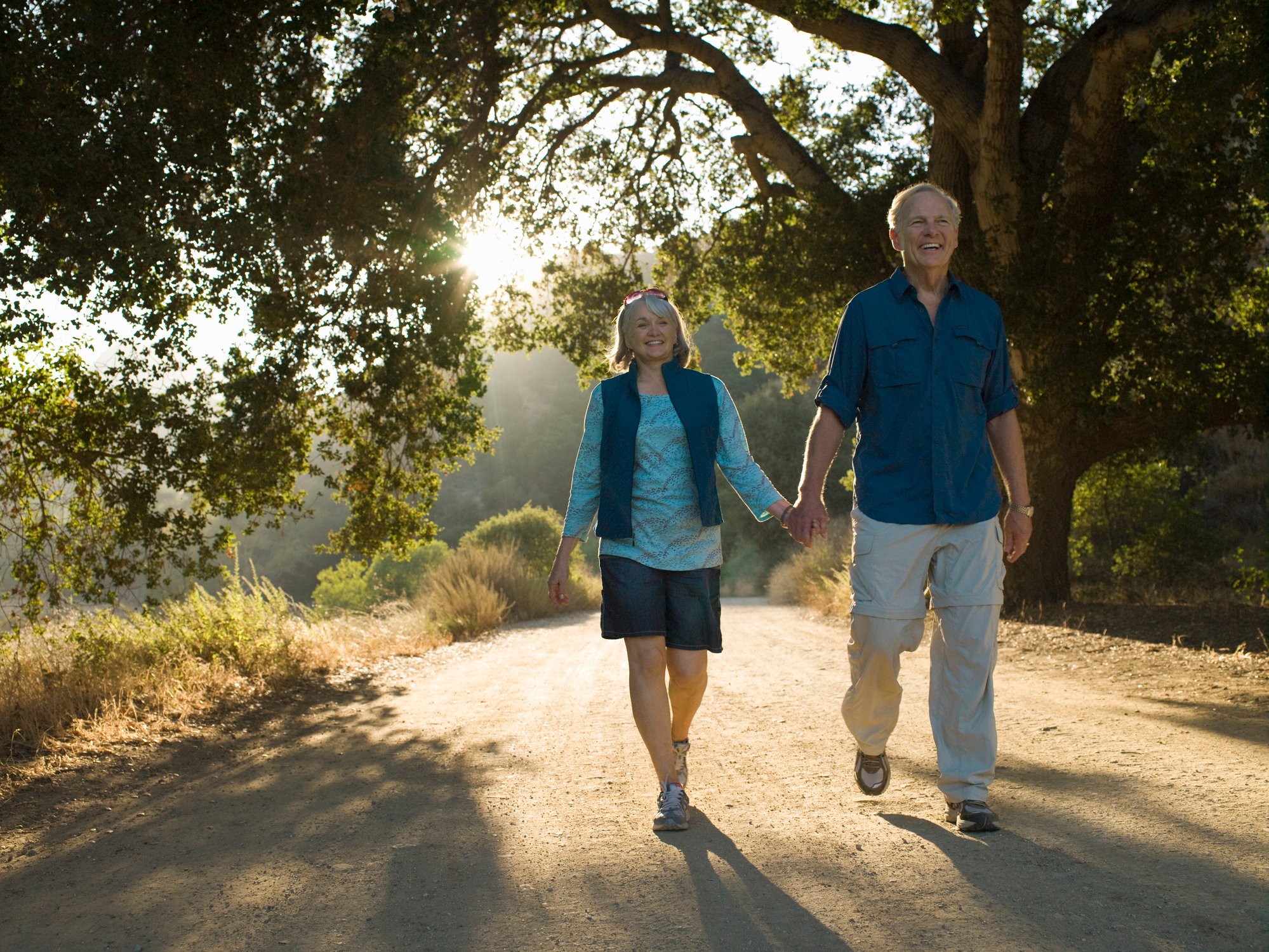 Retired couple holding hands while walking.