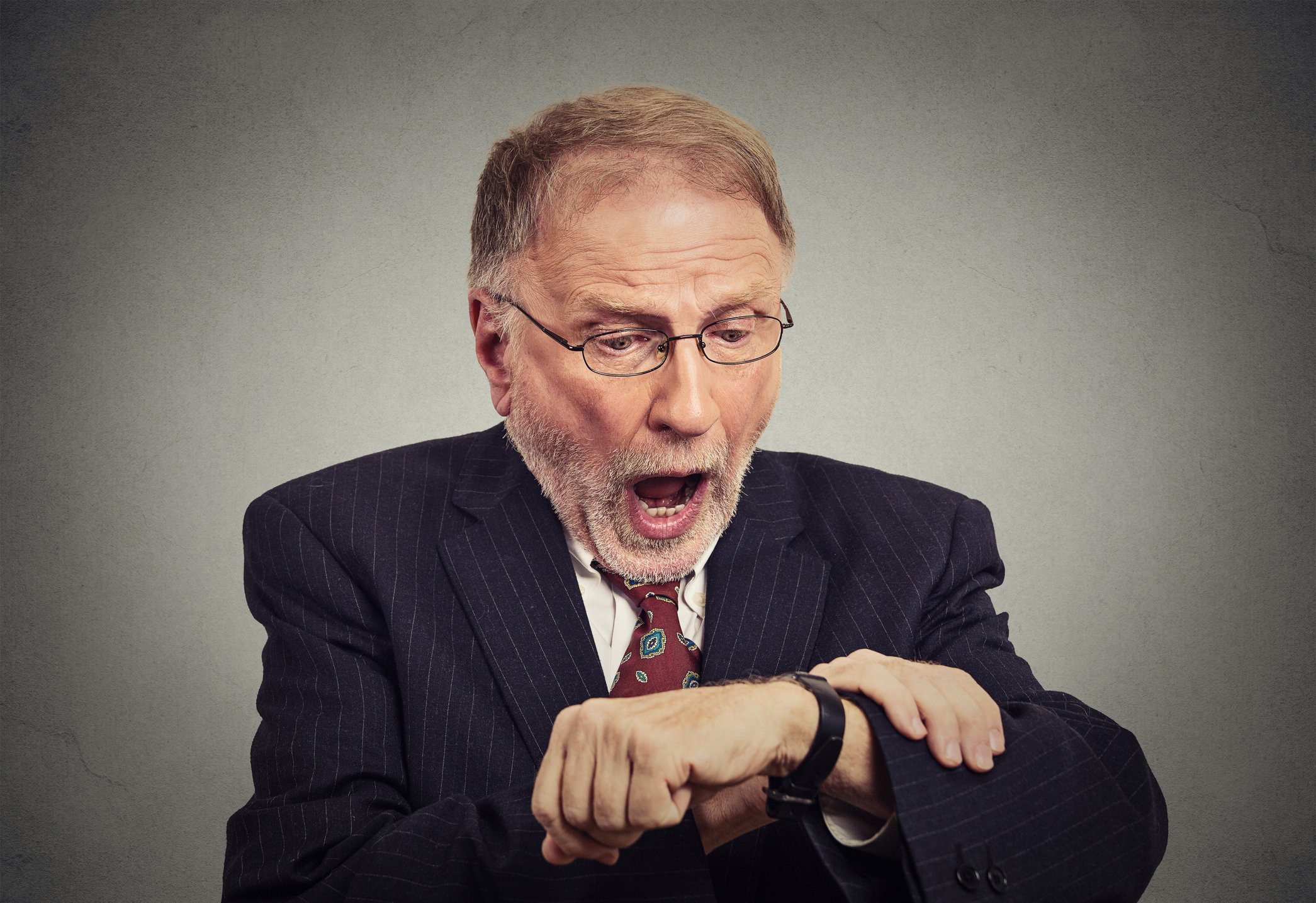 man in suit looking at watch and gasping in alarm