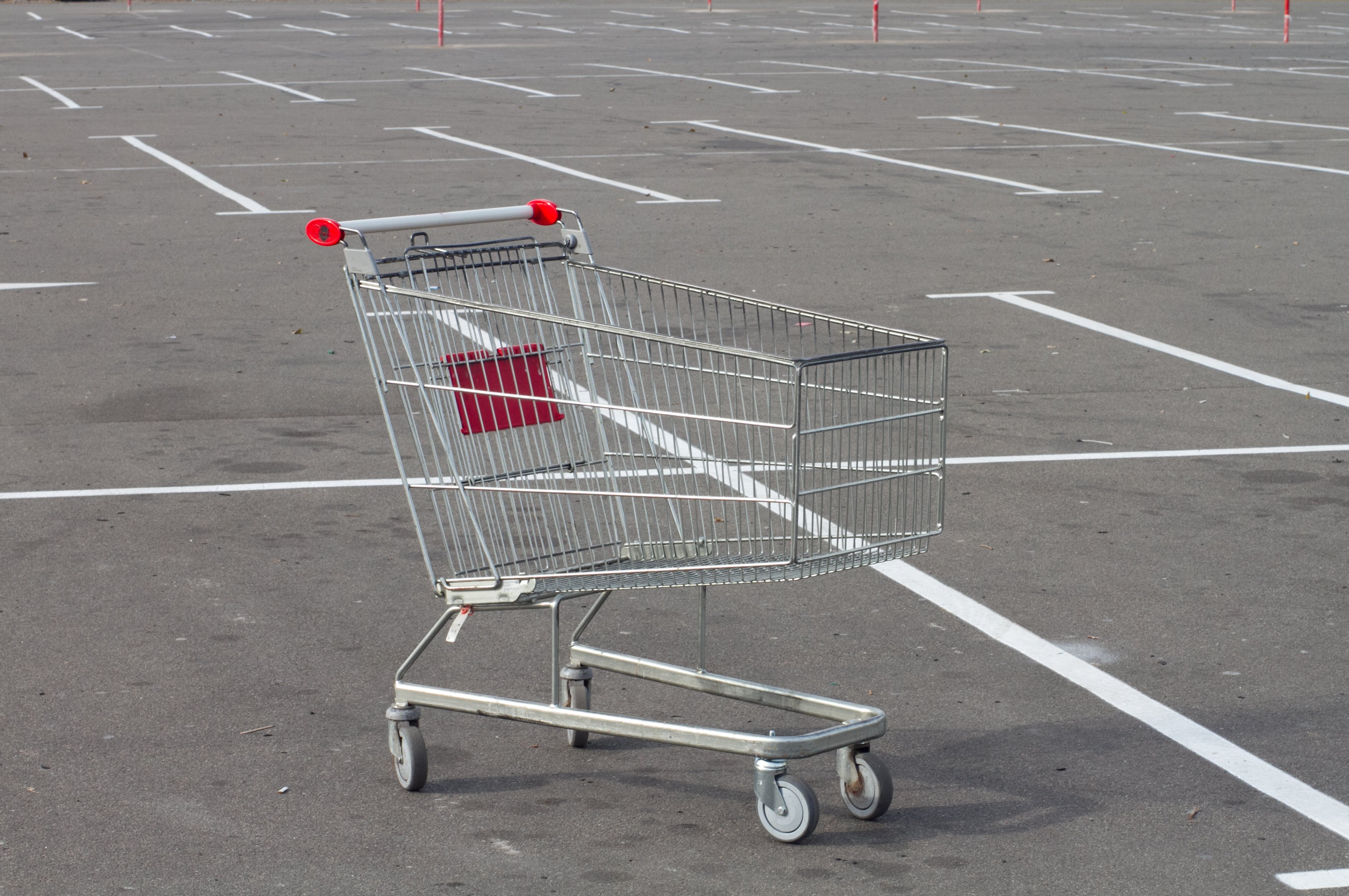 An empty shopping cart sitting in an empty parking lot.