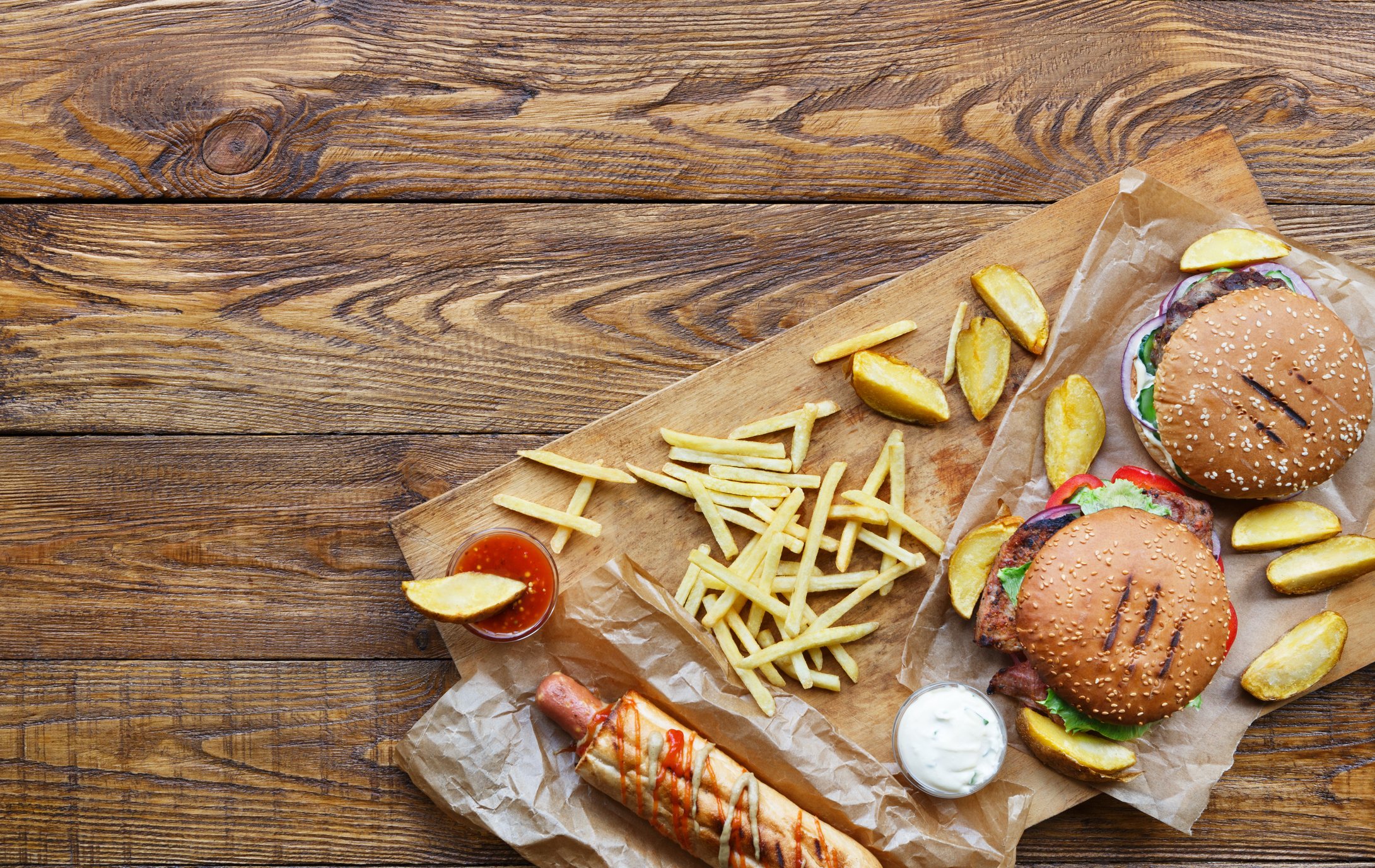 Burgers and fries sitting on a wooden table.