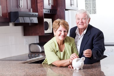 retired couple putting money into a piggy bank