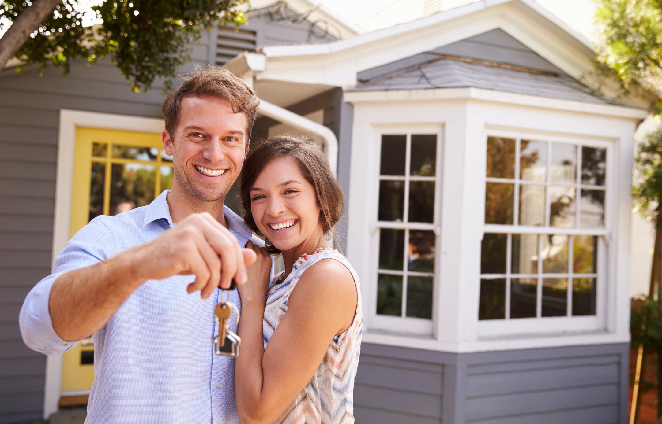 New homeowners outside a house holding their keys.