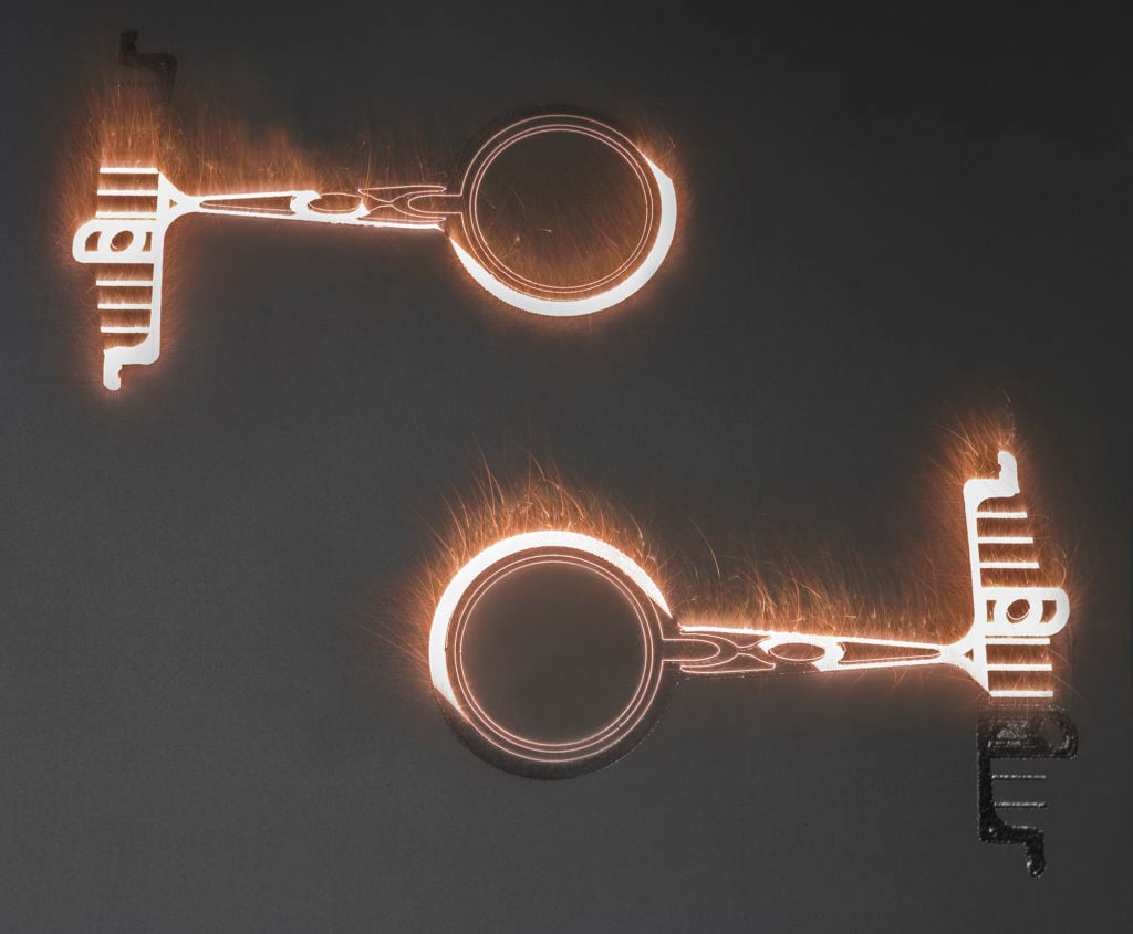 Process showing two metal parts being 3D printed.