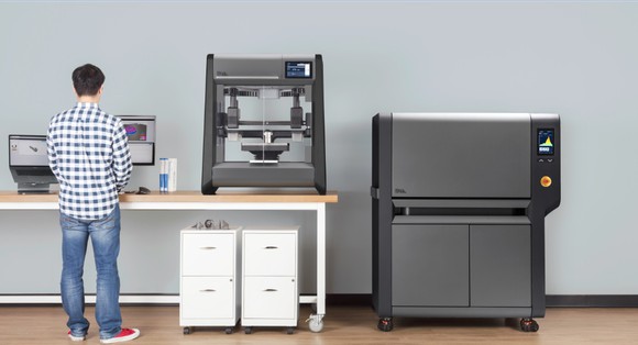 Man standing at a desk with a Desktop Metal 3D printer on it.