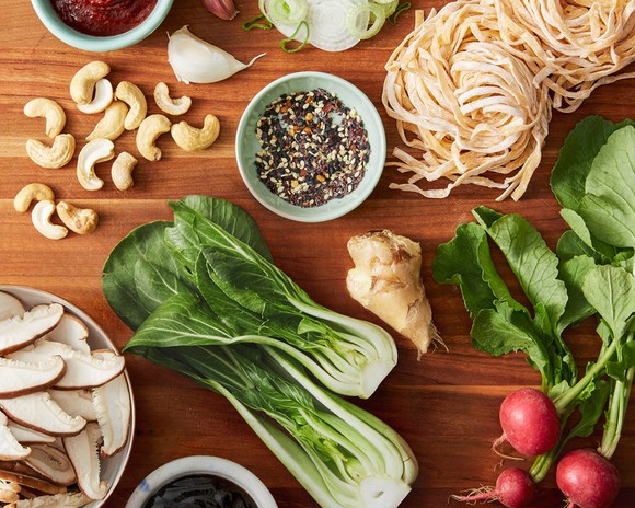 Various fresh meal kit ingredients arrayed on a wood table.