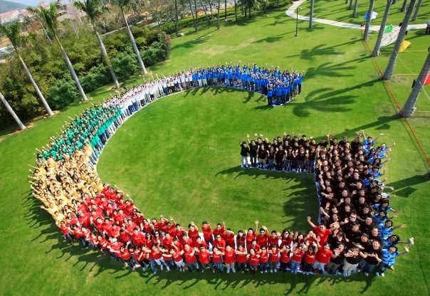 Google employees wearing colored shirts and making the Google logo