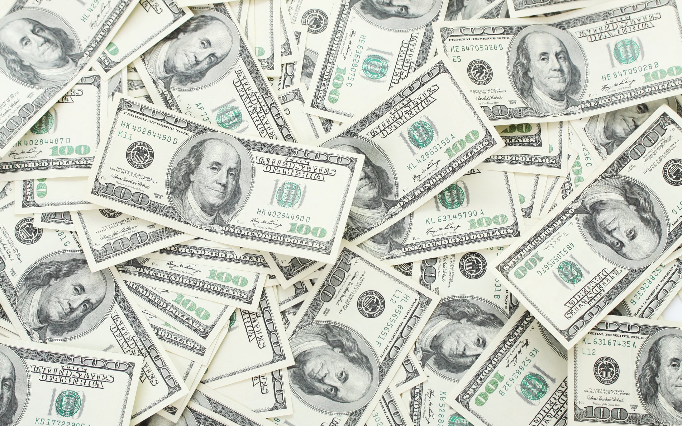 Hundred-dollar bills are scattered into a pile. 