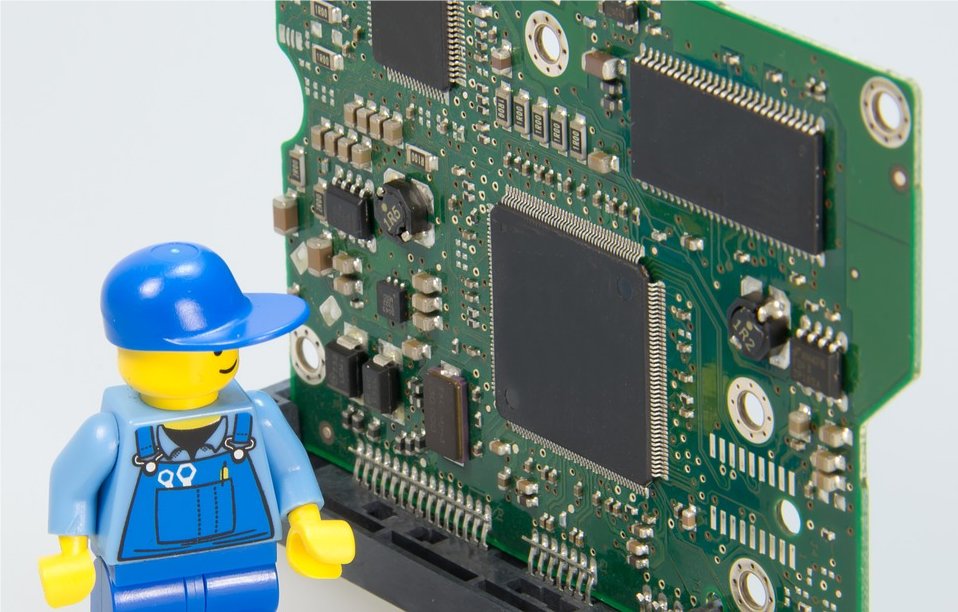 A Lego figure standing next to a circuit board.