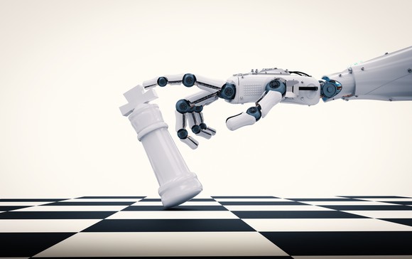 A robot arm tips over a king on a chess board.