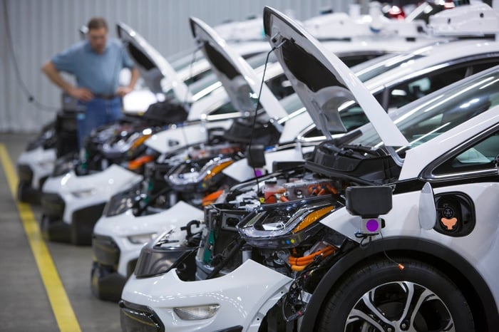 A lineup of driverless General Motors' Chevy Bolts sits inside a factory.