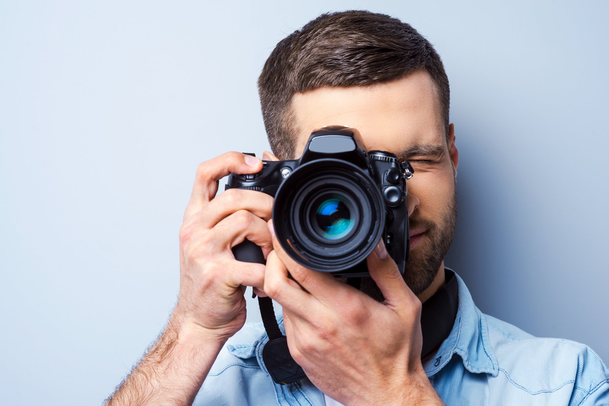 Man facing viewer with camera, about to take photo.