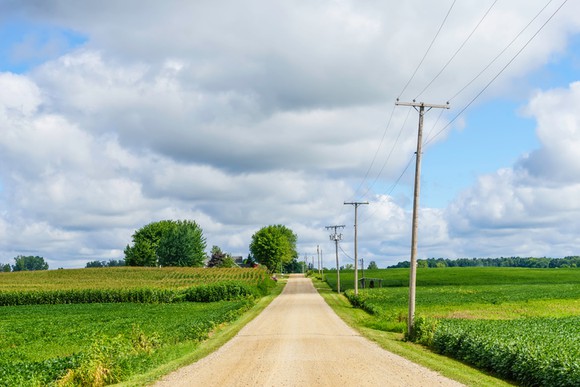 Telephone poles, carrying legacy telecom services like those offered by Frontier Communications, run down the side of a country road.