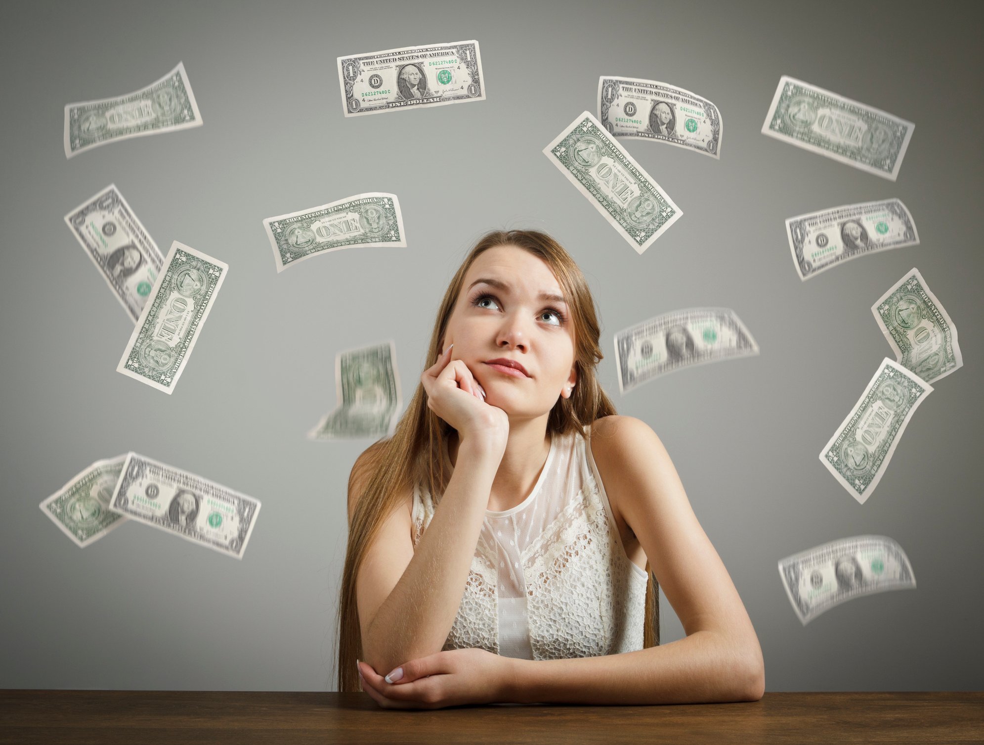 A young woman staring at falling dollar bills.